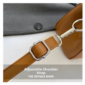 Close-up of adjustable brown leather shoulder strap with silver metal buckle and hook