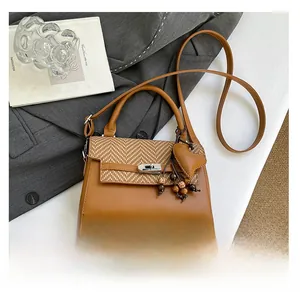 Detail of vintage crossbody bag with woven texture, leather heart charm and metal twist lock
