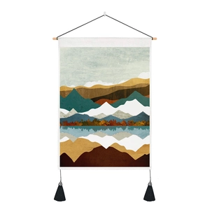 Close-up of abstract mountain landscape tapestry with black tassels and wooden hanging rod