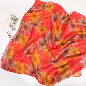 Detail of red floral voile scarf with yellow patterns and soft semi-transparent fabric