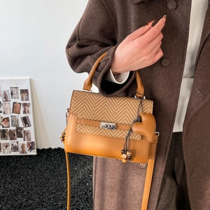 Brown woven leather Kelly bag with metal lock and heart charm shown on a model