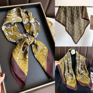 Détail d'un foulard en soie à imprimé cachemire or olive et bordure rouge contrastée
