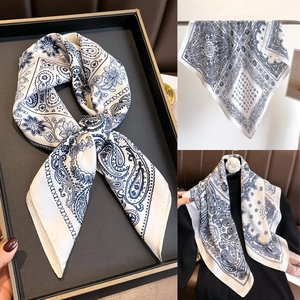 Détail d'un foulard carré en satin à motif cachemire bleu et blanc avec texture soyeuse