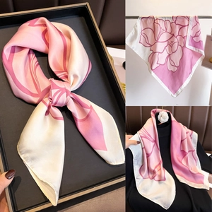 Vues détaillées d'un foulard en soie rose à fleurs, noué et porté sur un col noir