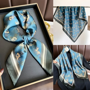 Détail d'un foulard en soie à imprimé carrosse vintage en coffret et porté sur pull