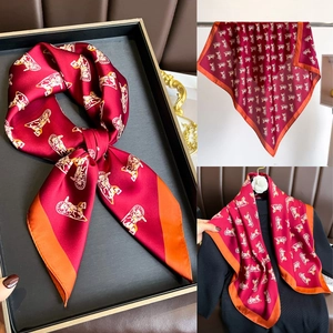 Détail d'un foulard en soie rouge avec imprimé calèche et bordure orange élégante