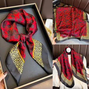 Détail d'un foulard en soie à fleurs et léopard sur un pull beige avec coffret