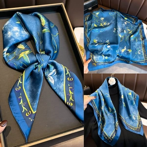 Détails du foulard en satin bleu avec motifs floraux et bordure jaune contrastée