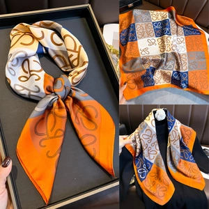 Vue détaillée d'un foulard en soie de luxe avec motif anagramme orange et bleu sur cuir