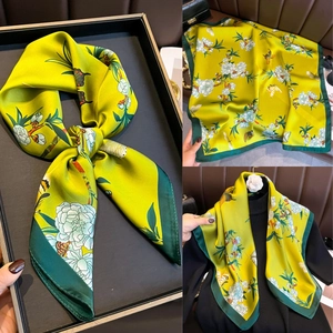 Détail du foulard carré en soie jaune vif avec bordures vertes et motifs floraux de papillon