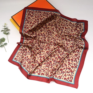 Detail of a square silk leopard print scarf with red borders and luxury gift box packaging