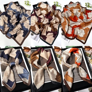 Detailed views of ginkgo leaf silk scarf in navy, red and orange colors shown tied