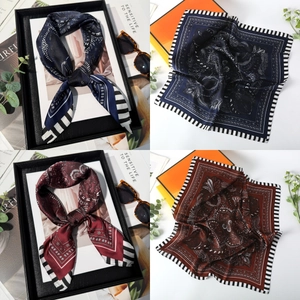 Detailed view of navy and auburn paisley silk scarves with striped borders in a gift box
