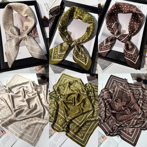 Detailed view of champagne and olive green silk-like scarves with ginkgo leaf prints