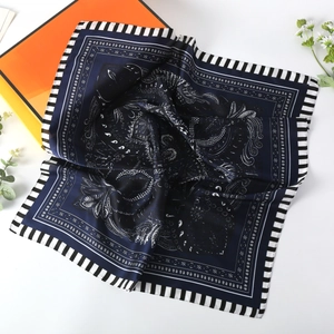 Detail view of navy blue paisley silk scarf with white floral patterns and striped edges