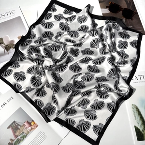 Artistic detail of a folded silk square scarf with shell patterns and stylish sunglasses
