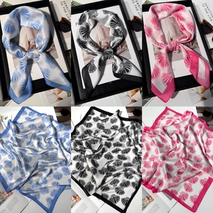 Detailed views of shell print silk scarves in blue, black, and pink with premium texture