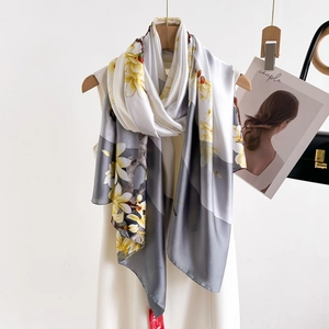 Elegant silk scarf with yellow magnolia print on white and grey background on hanger