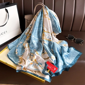 Macro detail of magnolia print on silk scarf draped over a luxury leather handbag