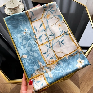 Close-up of sky blue silk scarf with magnolia print and elegant bamboo patterns