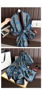 Détail d'un foulard en soie vintage bleu paon avec des motifs floraux satinés dorés