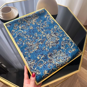 Gros plan sur le foulard en satin aux motifs floraux bleus et dorés de style ethnique
