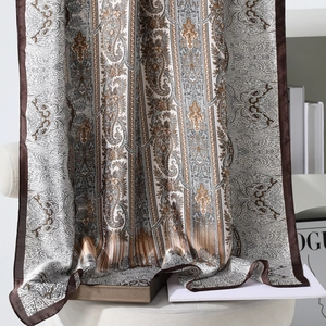 Elegant vintage paisley printed silk scarf in earth tones displayed on a minimalist stand