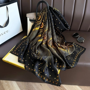 Detail of luxury silk scarf with black and gold sunburst pattern draped on a handbag