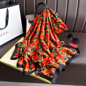 Detailed texture of a rose floral silk scarf draped elegantly over a luxury handbag