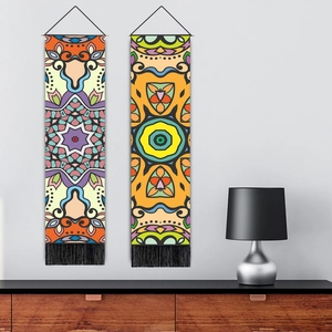 Tribal boho wall tapestry with colorful geometric patterns and black tassels hanging on wall