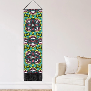 Bohemian tapestry with colorful geometric patterns and black tassels on a white wall