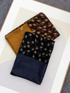 Flat lay detail of lightweight voile scarves with vintage floral prints and mustard yellow