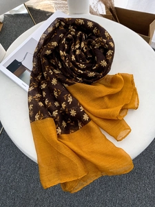 Detail of floral voile scarf in dark brown and yellow draped on a stool