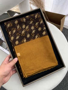 Close-up of floral voile scarf with mustard yellow panels in elegant gift packaging