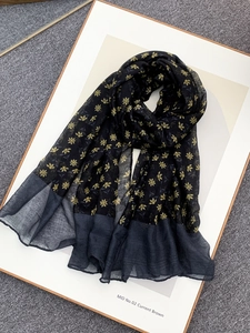 Detail of floral voile scarf with yellow patterns on grey textured carpet background