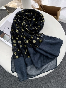 Macro detail of navy blue voile scarf with yellow floral print on minimalist white table