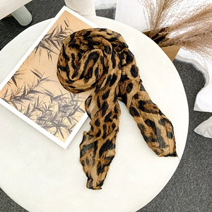 Detailed view of leopard print scarf with crinkled texture on a white surface