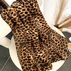 Fashionable leopard print velvet scarf for women displayed on a white stool in natural light