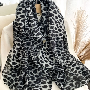Fashionable leopard print velvet scarf in black grey white draped on white knitwear