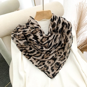 Detail of lightweight leopard print scarf draped over a white turtleneck sweater