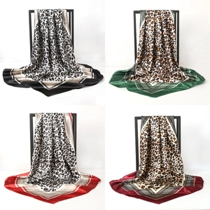 Quatre foulards en soie imprimé léopard en différentes couleurs sur un présentoir