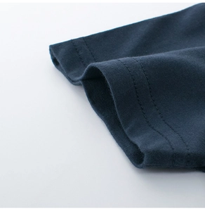 Détail de couture à double aiguille sur l'ourlet et le revers d'un t-shirt bleu marine