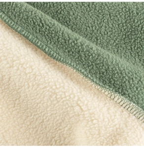 Close-up of green polar fleece and white sherpa lining with precision stitched edges