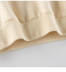 Close-up of a cream-colored sweatshirt ribbed hem showing premium cotton fabric texture