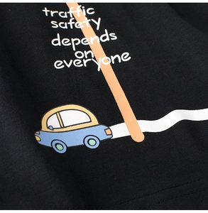 Close-up of cartoon car print and traffic safety slogan on black cotton toddler t-shirt