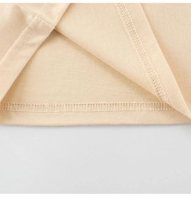 Détail de la double couture sur l'ourlet d'un t-shirt enfant en coton beige