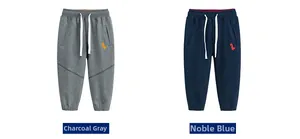 Detail of boys joggers in charcoal and blue featuring orange dinosaur embroidery