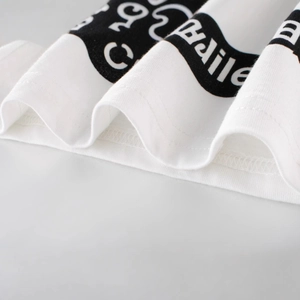Close-up of kids white cotton tank top hem with black letter print and neat double stitching