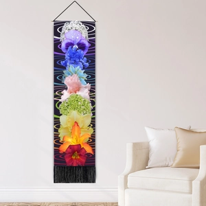 Bohemian floral wall tapestry with rainbow flower prints and black fringe hanging in a living room