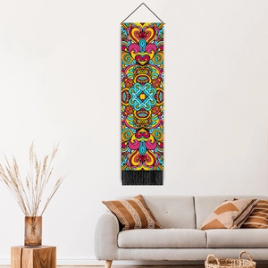 Bohemian mandala tapestry with colorful geometric patterns and black tassels on a white wall